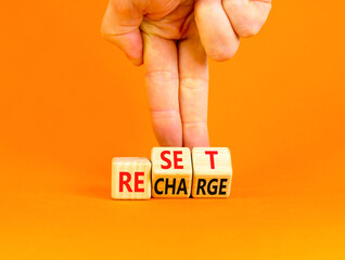 Reset and recharge symbol. Concept words Reset Recharge on beautiful wooden block. Beautiful orange...