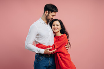 Happy couple embracing on pink background: expressing love and affection