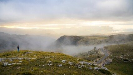 Hiker on misty mountain ridge at sunrise.
