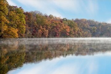 Autumnal trees in vibrant colors line the banks of a serene lake