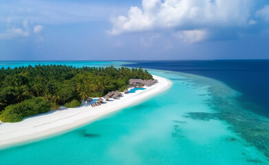 Obraz premium Aerial view of a tropical island with white sandy beach, turquoise water, and lush greenery under a sunny blue sky.