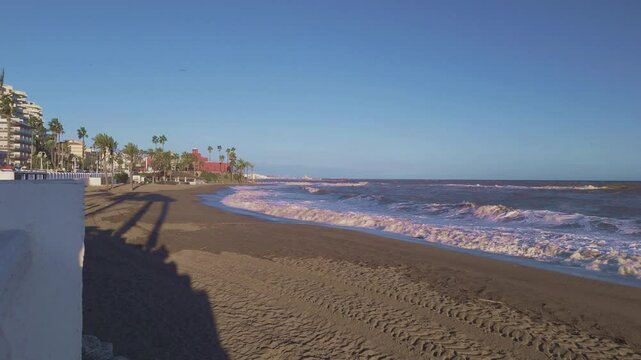 Benalmadena beach with breaking waves looking towards Bil Bil Castle after a windy day