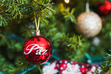 Red christmas ball wishing peace is hanging on christmas tree