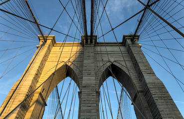 Obraz premium Brooklyn Bridge close up detail looking up at suspension cables at sunrise (beautiful landmark travel tourism destination in NYC) iconic New York City attraction over east river downtown Manhattan USA