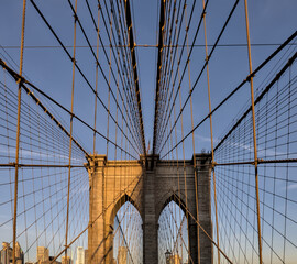 Obraz premium Brooklyn Bridge close up detail looking up at suspension cables at sunrise (beautiful landmark travel tourism destination in NYC) iconic New York City attraction over east river downtown Manhattan USA