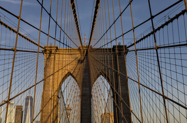 Obraz premium Brooklyn Bridge close up detail looking up at suspension cables at sunrise (beautiful landmark travel tourism destination in NYC) iconic New York City attraction over east river downtown Manhattan USA