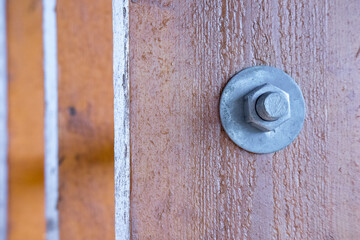 A metal screw with a nut screwed into a wooden board.