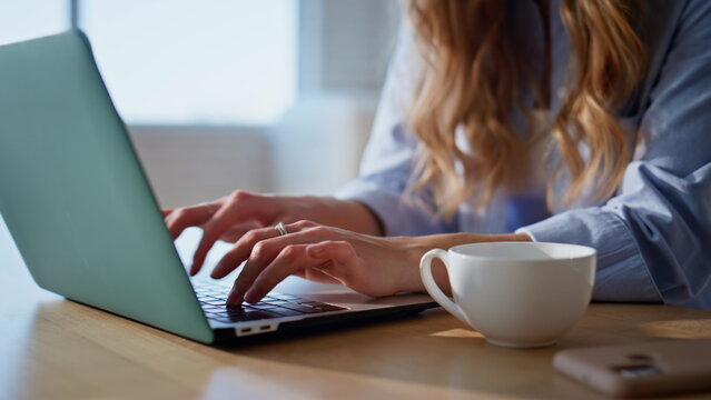 Closeup hands typing laptop keyboard on kitchen countertop. Remote woman working