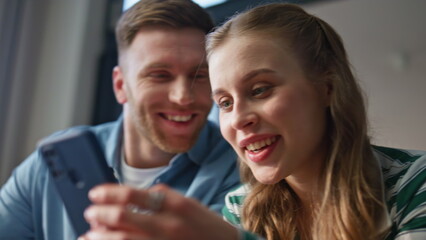 Closeup couple watching smartphone at living room together. Husband bonding wife