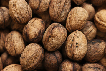 Heap of walnuts in shell, close-up, top view. Healthy eating. Harvest, agriculture. Walnuts, selective focus, background