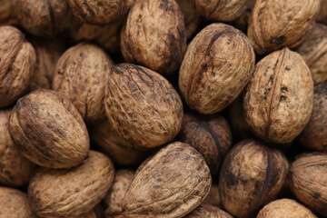 Heap of walnuts in shell, close-up, top view. Healthy eating. Harvest, agriculture. Walnuts, selective focus, background