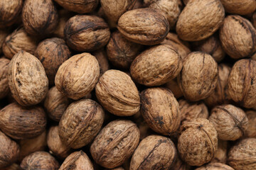 Heap of walnuts in shell, close-up, top view. Healthy eating. Harvest, agriculture. Walnuts, selective focus, background