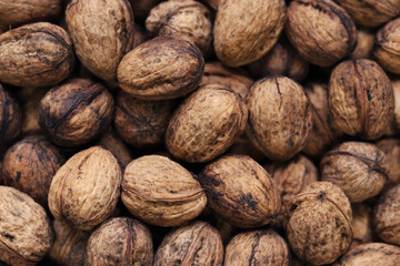 Heap of walnuts in shell, close-up, top view. Healthy eating. Harvest, agriculture. Walnuts, selective focus, background