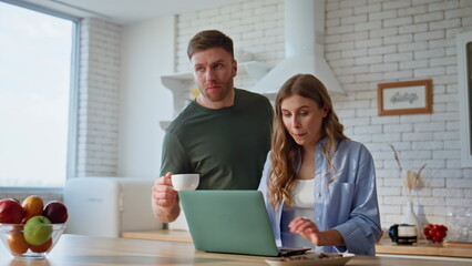 Happy couple planning vacation looking laptop kitchen closeup. Spouses talking