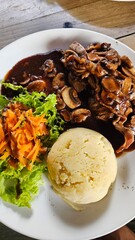 Delicious steak dinner with mushroom sauce, mashed potatoes, and a side salad.  Enjoy!