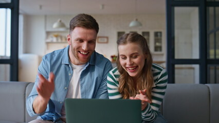 Joyful couple waving hands talking laptop emotionally. Laughing pair video call