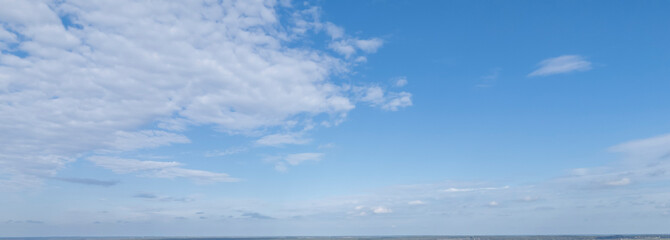 A clear blue sky with fluffy white clouds creating a serene atmosphere over the horizon. Perfect for nature and outdoor themes.