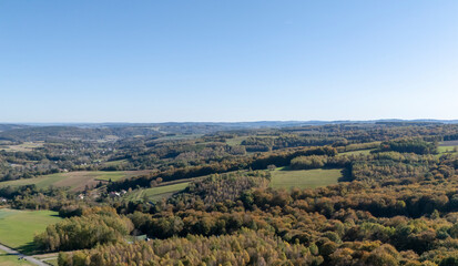Aerial view of a vast landscape showcasing an expanse of colorful autumn foliage under a clear blue sky.