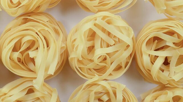 Top down view. Slider shot of a stack of uncooked Italian tagliatelle pasta. Raw dried spiral pasta. Italian Cuisine, Pasta and Grains, Mediterranean Diet concepts. 4k