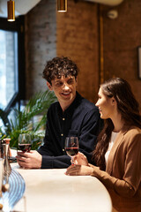 A young couple enjoys a charming Valentines Day dinner, sharing smiles and drinks.