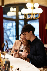 A young couple enjoys fine wine at a cozy restaurant, celebrating their love on Valentines Day.