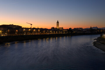Fototapeta premium Sunset view of the Adige River and the tower of the Basilica of St. Zeno in Verona, Italy, December 2024