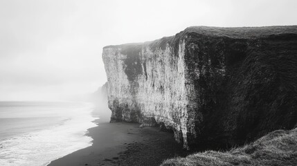 Misty coastal cliffs overlooking a serene beach in black and white capturing nature's rugged beauty...