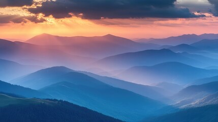 Aerial view of majestic blue mountain landscape at sunset with vibrant sunlight and dramatic clouds illuminating serene valleys and hills