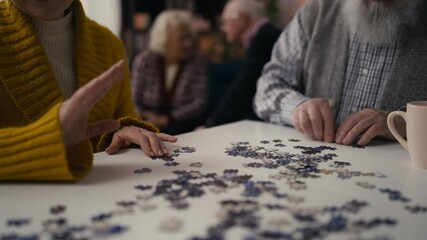 Senior people connect jigsaw pieces in a nursing home, enhancing motor skills