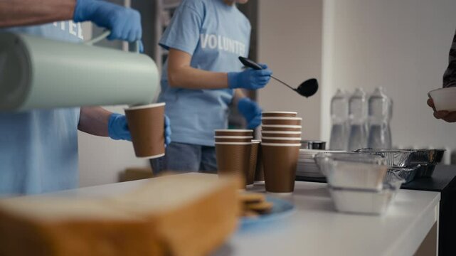 Close-up of volunteers serving soup and hot drinks to the people in need