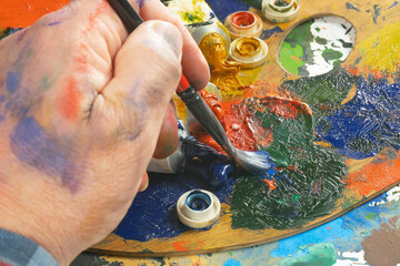 Painter holding paintbrushes in his hands, close-up