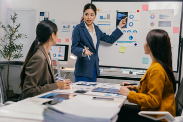 Businesswomen in modern office discuss marketing strategies, analyzing charts and planning. Teamwork and collaboration drive success in this dynamic workplace