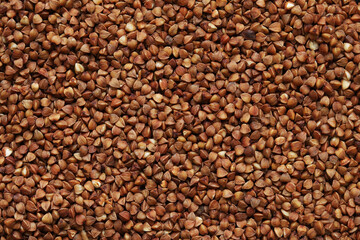 Buckwheat groats, top view. Raw large buckwheat grains, uncooked porridge. Buckwheat background. Raw buckwheat texture background, brown grains pattern