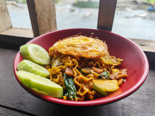 Mie Goreng Close Up, Fried Instant Noodles with Sunny Side Up Egg and Vegetables on Top. Popular Instant Noodles from Indonesia.
