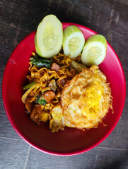 Mie Goreng Close Up, Fried Instant Noodles with Sunny Side Up Egg and Vegetables on Top. Popular Instant Noodles from Indonesia.