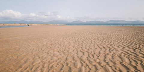 Panoramic view of the sand in newborough beach with snowdonia in the background