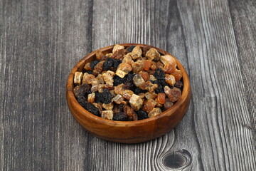 Mix of nuts and dried fruits in wooden bowl isolated on a wooden background.