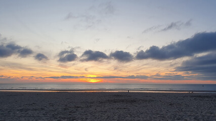 Walking on a beach at sunrise. Sand, sea and sky.