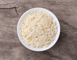 Cooked white rice in a bowl over wooden table