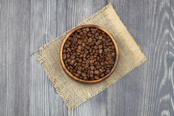 Wooden bowl with coffee beans on wooden background