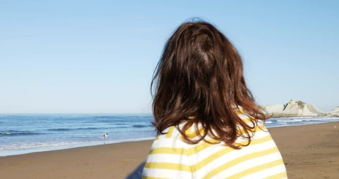 Mujer feliz en la playa disfruta del sol de los primeros d&iacute;as de primavera con su perro 