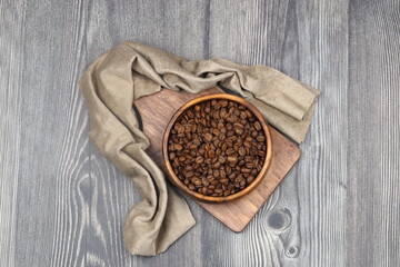 Wooden bowl with coffee beans on wooden background