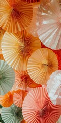 A bunch of paper fans are hanging from the ceiling, with some orange and some pink