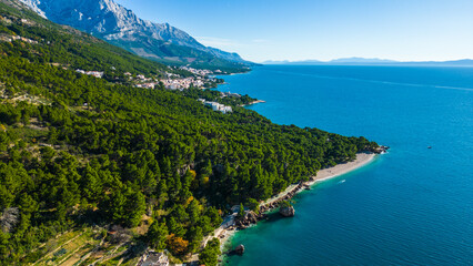 Fototapeta premium A stunning aerial view of Brela, Croatia, showcasing the iconic Kamen Brela rock formation surrounded by crystal-clear turquoise waters. The coastline is dotted with pristine beaches