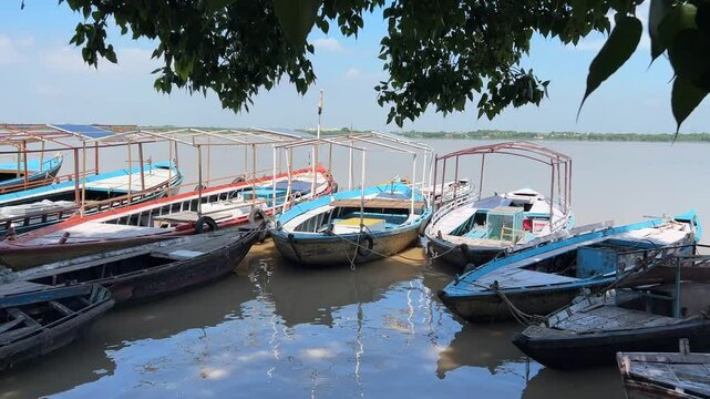 Boats anchored on the Ganges River on a sunny day in Assi ghat, Varanasi city, Uttar Pradesh, India