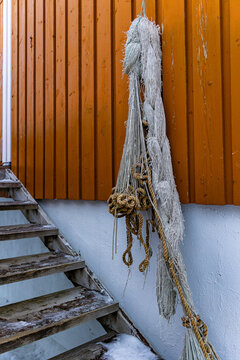 Old fishing nets hang on color wooden walls of traditional fishing cabin rorbur in Norway