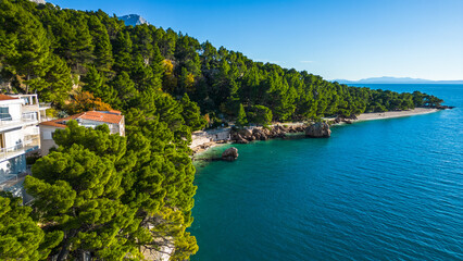 Naklejka premium A stunning aerial view of Brela, Croatia, showcasing the iconic Kamen Brela rock formation surrounded by crystal-clear turquoise waters. The coastline is dotted with pristine beaches