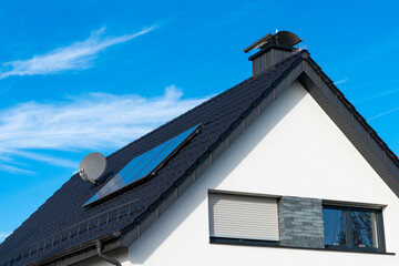 Modern house with solar panels and satellite dish on clear day