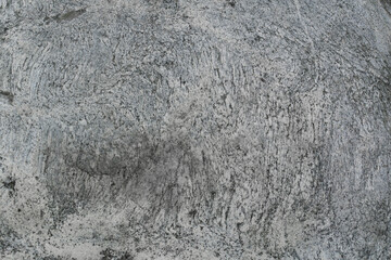 Stone texture: A close-up of the rough texture of a stone with characteristic cracks, mineral inclusions, and natural shades of gray and beige. The stone's surface looks massive and resembles ancient 