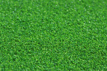 Fototapeta premium Artificial green grass mat, selective focus. Artificial turf, surface made of synthetic fibers. Green grass texture background. Short artificial grass golf surface